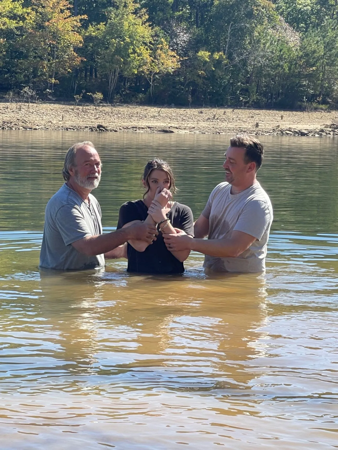 A Cornerstone Church baptism taking place in a lake with two church leaders beside the person being baptized